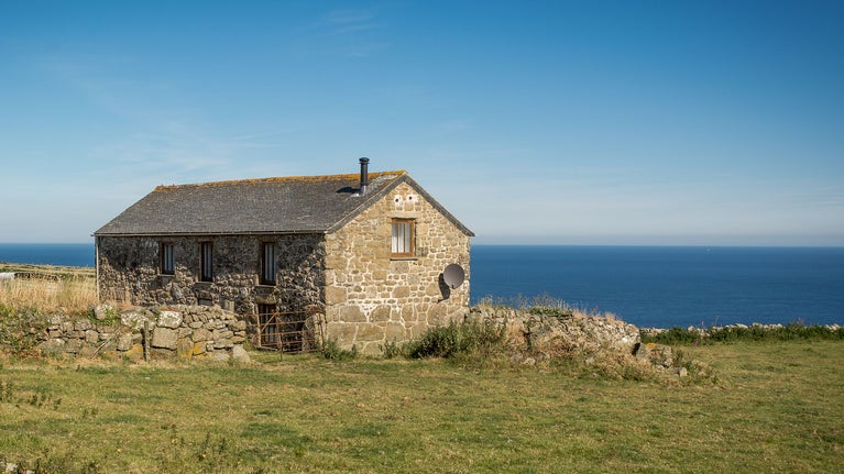 Bosigran Cottage with a field in the foreground and the sea in the background, Cornwall